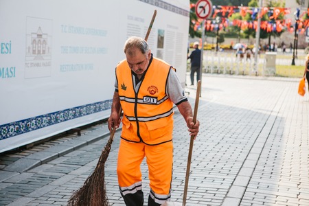 Istanbul, June 15, 2017: janitor in bright orange uniform sweeping the tile on the street in Sultanahmet district.のeditorial素材