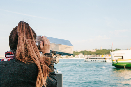 Brunette girl looking at the sea through tourist telescope.の写真素材