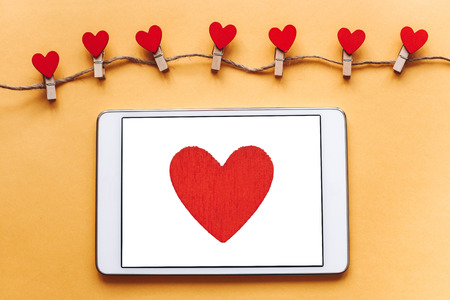 Top view. Red heart on the tablet screen.