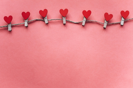 Clothespins in the form of hearts on a pink background.の写真素材