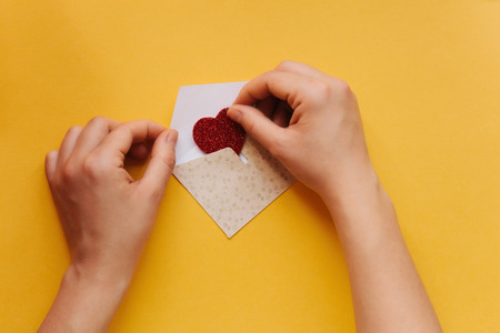 The girl wrote a letter with congratulations and pastes the envelope with a symbol in the form of a...