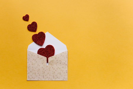 Envelope with symbols in the form of red hearts on a yellow background. Celebration.の写真素材