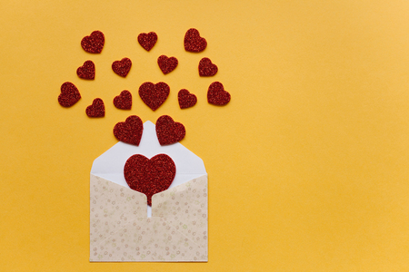 Envelope with symbols in the form of red hearts on a yellow background. Celebration.の写真素材