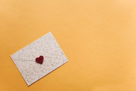 Envelope with a symbol in the form of a red heart on a yellow background.