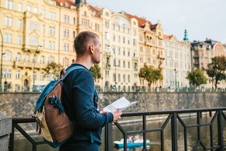 A tourist with a backpack in front of a beautiful old architecture in Prague in the Czech Republic. He looks at the map.の写真素材