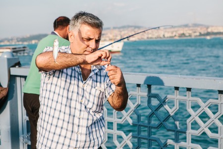 Istanbul, June 15, 2017: A fisherman from the local population stands on the Galata bridge and fishes. Traditional hobby of the inhabitants of Istanbul.のeditorial素材