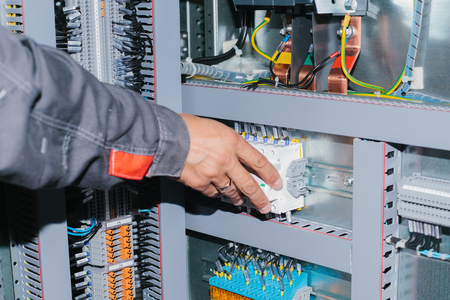 Electrician specialist checking low-voltage cabinet equipmentの写真素材