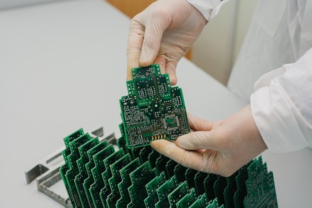 The technician takes a computer board with chips. Spare parts and components for computer equipment. Production of electronics and maintenance. The concept of high technology.の写真素材