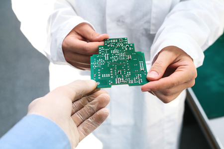 Technician with computer circuit board with chips. Spare parts and components for computer equipment. Production of electronics and maintenance. The concept of high technology.の写真素材