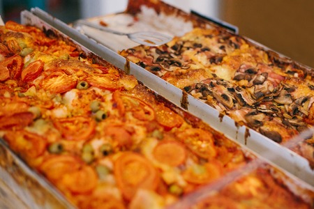 A delicious baked traditional pizza with cheese, tomatoes, mushrooms and olives is sold in the...