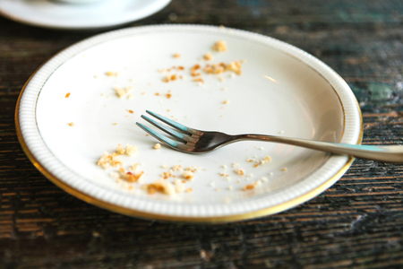 Conceptual image of the end of the holiday is an empty plate with crumbs and a fork on it.の写真素材