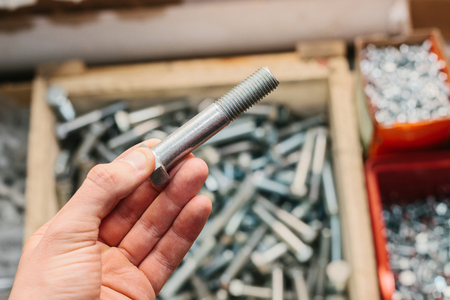 A man is holding a building bolt. Many different fastening tools used in construction and repair.の写真素材