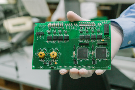 Technician with computer circuit board with chips. Spare parts and components for computer equipment. Production of electronics and maintenance.の写真素材