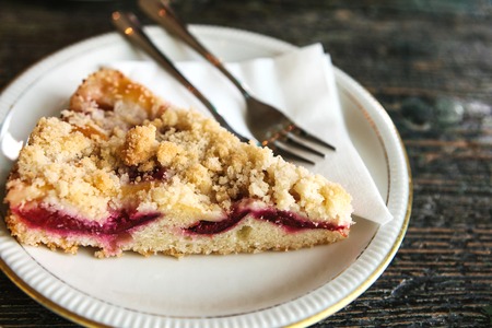 Piece of sweet pie with dessert fork on a plate on a wooden surface in the cafeの写真素材