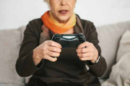 An elderly woman is playing a video game. Elderly person and modern technology.の写真素材