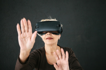 An elderly woman in virtual reality glasses. An elderly person using modern technology.の写真素材