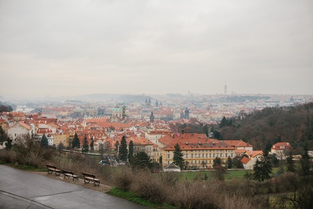 Typical roofs in Prague. Top view - roofs with red tiles in old buildings in Prague. Europe. Empty benches stand in a row. View in winter.の写真素材