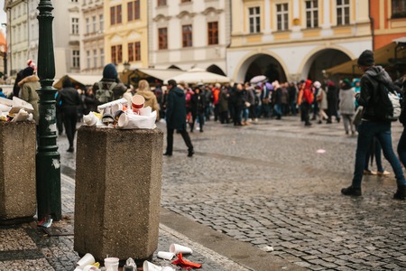 A crowded trash can on Pragues main square during the Christmas break. Many people are blurry in the background. Pollution of city streets with trash on holidays.の写真素材