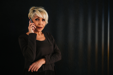 A successful positive elderly female consultant is negotiating a cell phone. Communication between people using modern technology.の写真素材