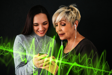 An elderly woman and a young girl listen to music together. Communication between people of different generations.の写真素材