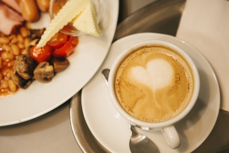 Traditional English breakfast. A cup of coffee with cappuccino is next to it. National food. A famous dish all over the world.の写真素材