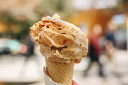 Ice cream in the horn in the foreground, the street is blurred in the background. Sweet and tasty foodの写真素材