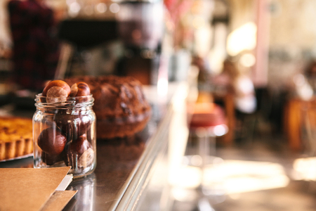 The counter in the cafe is a blurred background. Nuts in the bank in the foreground, interior of the cafe in the backgroundの写真素材
