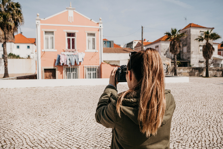 A street photographer or a young woman takes pictures of authentic houses in Lisbon in Portugal. A professional photographer or tourist taking pictures for memoryの写真素材