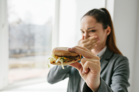 A young girl shows that she does not like a burger. Conceptual image of refusal from unhealthy eating.の写真素材