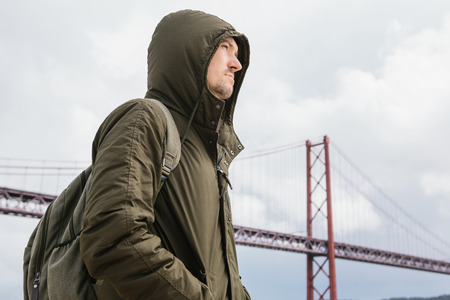 A young traveler or a tourist with a backpack on the waterfront in Lisbon in Portugal next to the...