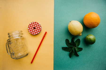 Conceptual photography. Citrus lemonade or juice. On one side there is a glass jar and a tube. On...