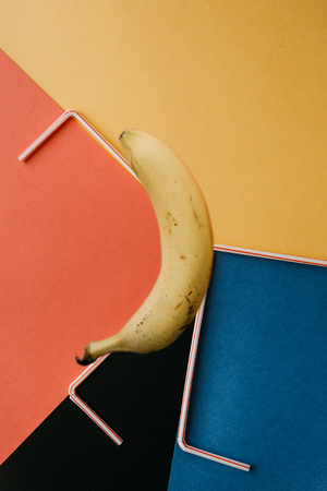 A creative photograph with a banana and small tubes on a bright backgroundの写真素材