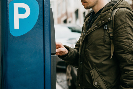 A person or a tourist pays for car parking in a street parking machineの写真素材
