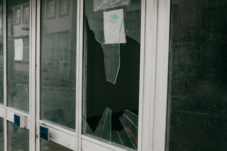 A broken window in a residential building or store as a result of an earthquake or vandalism or other negative event. Abandoned building.の写真素材