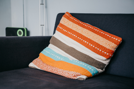 A colored pillow on the sofa in the living room. Cozy atmosphere.
