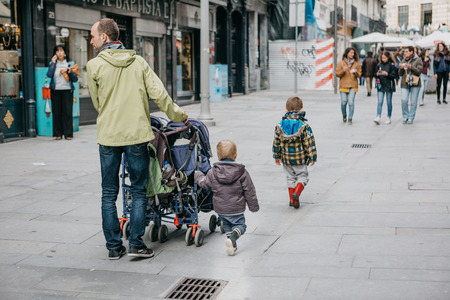 Portugal, Porto, 05 May 2018: A young father walks with his young children along a city street.のeditorial素材