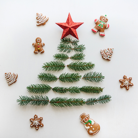 Creative idea for Christmas or New Year theme. A Christmas tree from spruce branches and a star on top. Nearby lie gingerbread cookies. Celebratory concept.の写真素材