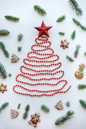 Creative idea for Christmas or New Year theme. A Christmas tree made of beads and a star on top. Next to it lie the traditional gingerbread and spruce branches for decoration.の写真素材