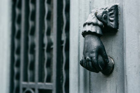Close-up. Vintage handle for knocking on the door in the form of a hand. Entrance to the apartment building.の写真素材
