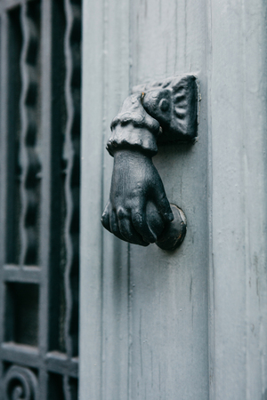 Close-up. Vintage handle for knocking on the door in the form of a hand. Entrance to the apartment building.の写真素材