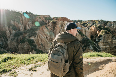 A tourist with a backpack or traveler walks through the hilly terrain.の写真素材
