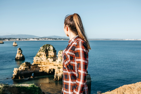 The girl admires a beautiful view of the Atlantic Ocean off the coast of Portugal next to the city called Lagos.の写真素材