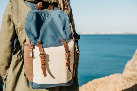 A tourist girl or a traveler with a backpack admiring the beautiful view of the Atlantic Ocean in Portugal.の写真素材