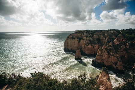 Beautiful view of blue or turquoise water and waves with foam of the Atlantic Ocean next to the rocks off the coast of Portugalの写真素材