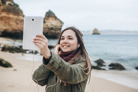 A young woman tourist or blogger communicates on the tablet through the Internet or stories will tell its subscribers about what is happening.の写真素材