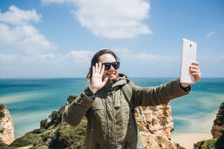 A young woman tourist or blogger communicates on the tablet through the Internet or stories its...