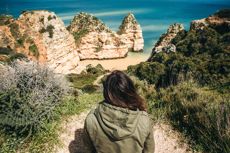 A young woman tourist enjoys the beautiful views of the Atlantic Ocean and the landscape off the coast in Portugal.の写真素材