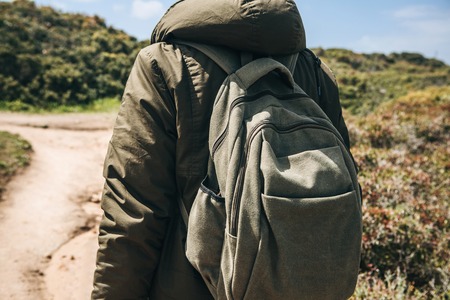 A tourist with a backpack or traveler walks through the hilly terrain.