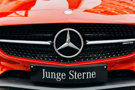 Berlin, August 29, 2018: A close-up of the Mercedes Benz sign on the new red Mercedes-Benz AMG GT. The inscription in German is translated as young stars.のeditorial素材