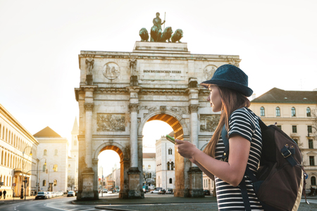 A tourist girl with a backpack looks sights in Munich in Germany. Passes by the triumphal arch.の写真素材